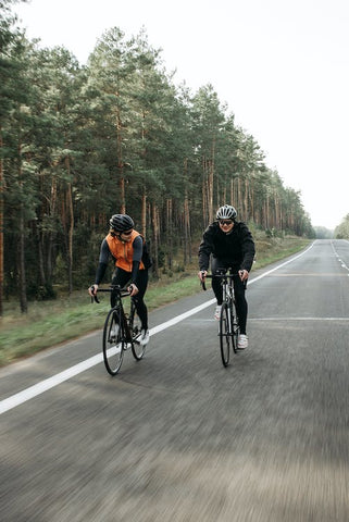 two cyclists cycling a bike on the road