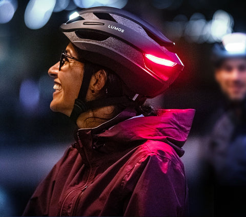 a woman with a Lumos helmet at night smiling and looking up