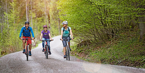 A family cycling on the road surrounded by trees