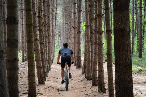 a cyclist on a bike cycling through a forest with the helmet on his head
