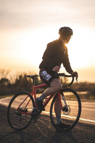 [an image showing cyclists on the road with bike equipment looking at the sun