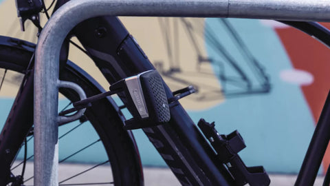 An image of a cyclist riding a bike equipped with ABUS Bordo Lock. The cyclist is shown confidently navigating a city street, highlighting the convenience and security provided by ABUS Bordo Locks. The lock is folded and securely attached to the bike frame, demonstrating its portability and ease of use. This image represents the importance of using a reliable bike lock to protect your valuable bicycle while enjoying your cycling adventures]