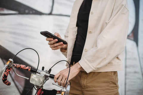 A man using smartphone while standing on street near bicycle